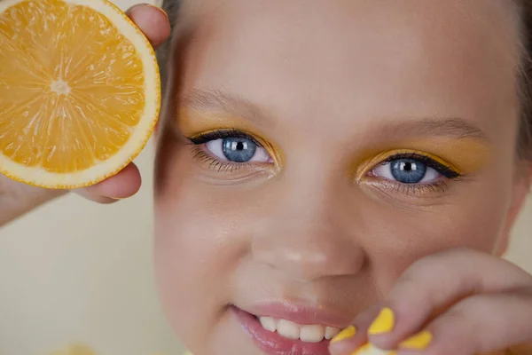 Charming tween girl with slices of ripe lemon on yellow background. juicy fruit concept. summer — Stock Photo, Image