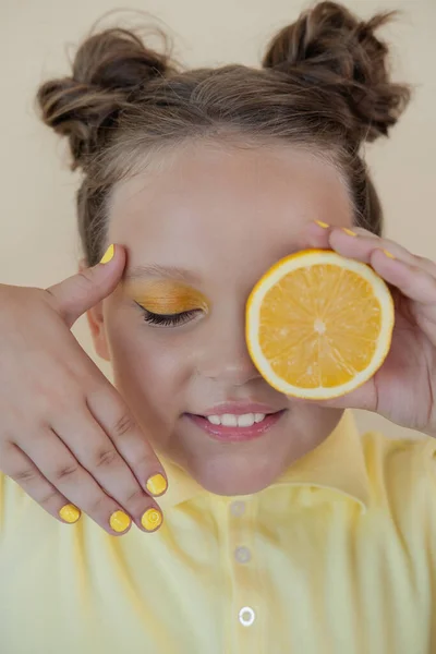 Preteenager girl with lemon on yellow background. child with fruit — Stock Photo, Image