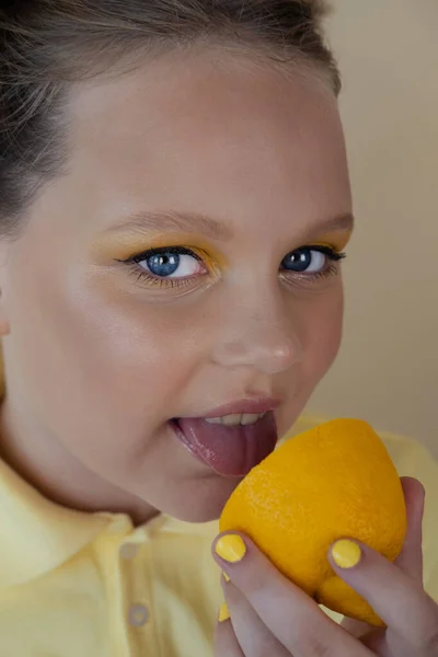 Charming tween girl with slices of ripe lemon on yellow background. juicy fruit concept. summer — Fotografia de Stock