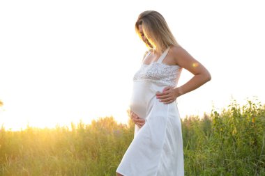 Müstakbel anne bebek bekliyor. Uzayı kopyala Hamilelik, annelik, beklenti konsepti. Dışarıda koca göbekli beyaz gecelikli güzel bir kadın.