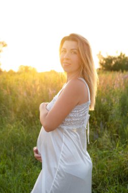 Müstakbel anne bebek bekliyor. Uzayı kopyala Hamilelik, annelik, beklenti konsepti. Dışarıda koca göbekli beyaz gecelikli güzel bir kadın.