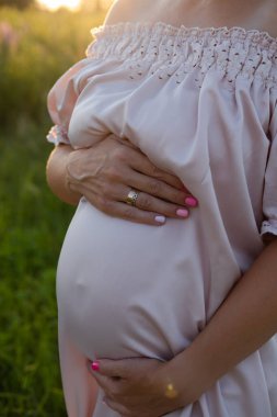 Gün batımında hassas hamilelik portresi. Annemin dışarıda pembe elbiseli olmasını bekliyordum. Hamileliğin güzel ve hassas fotoğrafı.