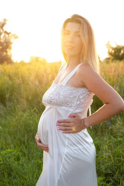 Müstakbel anne bebek bekliyor. Uzayı kopyala Hamilelik, annelik, beklenti konsepti. Dışarıda koca göbekli beyaz gecelikli güzel bir kadın.