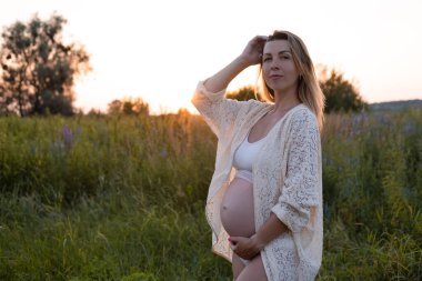 Müstakbel anne bebek bekliyor. Uzayı kopyala Hamilelik, annelik, beklenti konsepti. Dışarıda koca göbekli beyaz gecelikli güzel bir kadın.
