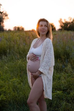 Müstakbel anne bebek bekliyor. Uzayı kopyala Hamilelik, annelik, beklenti konsepti. Dışarıda koca göbekli beyaz gecelikli güzel bir kadın.