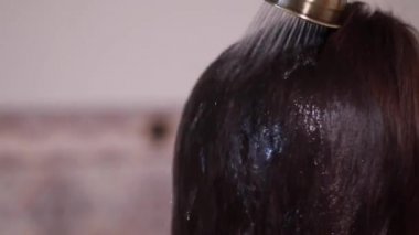 Back view of young brunette woman taking shower in bathroom. Washing healthy long hair in the morning. Daily routine lifestyle photo.