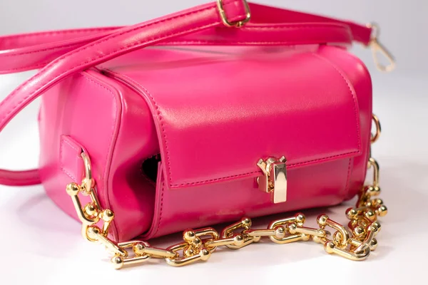 Beyaz arka planda izole edilmiş altın zincirli pembe küçük el çantası. Ürün fotoğrafçılığı. Çantalar ve çantalar.
