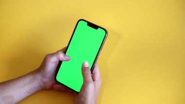 Chroma tuşu elinde akıllı telefondan model alınıyor. Genç çocuk yeşil ekran düzenli telefon kullanır, renk anahtarı, içeriği izler, oyun oynar. Fotokopi için yeşil ekran kullan. Yavaş çekim.