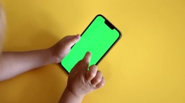 Yakın çekim anaokulu kızı elinde yeşil ekran planlı akıllı telefon tutuyor. Şablon video malzemeleri. Sahte uzay telefonu kopyala. Renk Anahtarı, Görünüm İçeriği, Videolar, Tap on Screen, Play Online Games. Yavaş çekim.