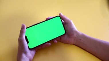 Yeşil ekran. Çocuk elinde bir Smartphone tutuyor. Yakın plan bir oyun oynuyor. Boş yeşil ekranlı telefon reklam için görüntüyü oluşturur. Yavaş çekim.