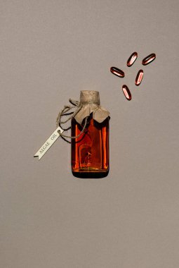 İçi yosun bazlı yağ ve birkaç jelatin yağı kapsülü ile dolu şeffaf bir kap. Cam şişe, ahşap etiketli jüt ipliğiyle bağlanmış. Kahverengi kağıt arka plan. Yenilikçi gıda malzemesi. Boşluğu kopyala.