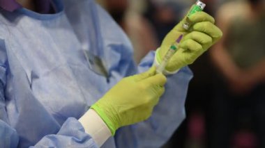 Doktor aşıyı şırıngaya çeviriyor, görüntüyü kapat. Coronavirus hastalığının önlenmesi. Aşılama süreci