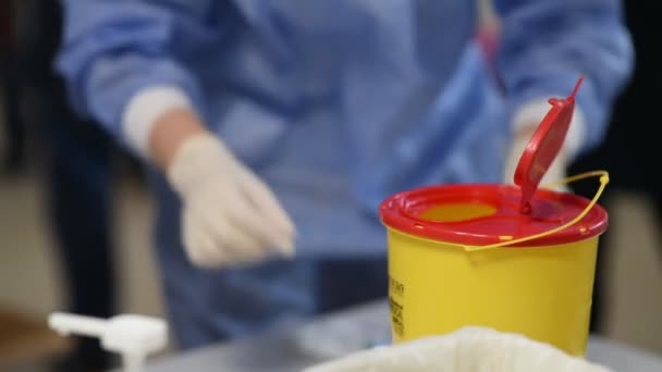 의사는 주사기와 폐기물을 플라스틱 용기에 던진다 — 비디오