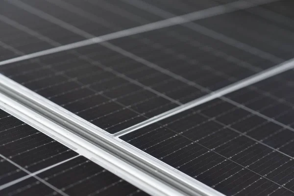 Rooftop solar power system. Black solar panels, close up view. Small drops of water on the surface of the panels after rain. Industrial background with copy space.