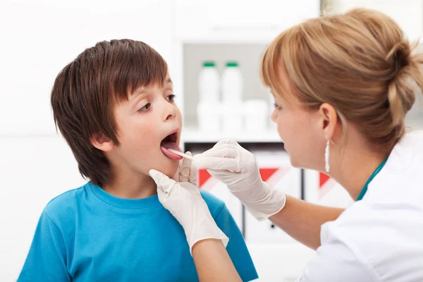 Доктор проверяет горло маленького мальчика — стоковое фото