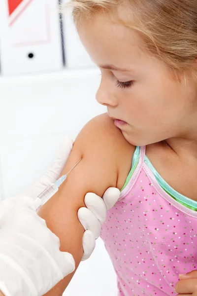 Маленькая девочка получает инъекцию или вакцину — стоковое фото