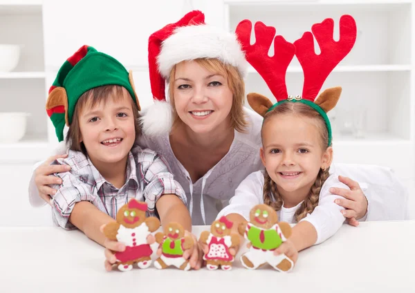 Mulher feliz com crianças em chapéus de Natal segurando gingerbread peop — Fotografia de Stock