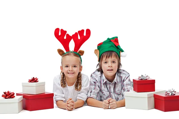 Des enfants heureux avec des chapeaux d'elfe et de renne posés parmi les cadeaux — Photo