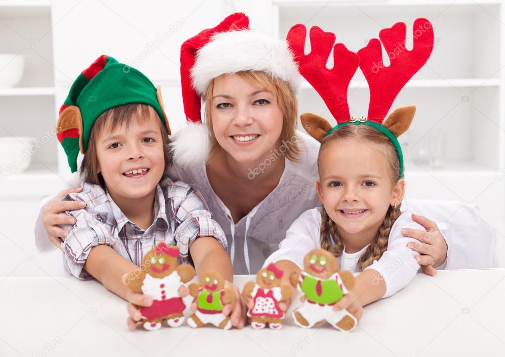 Happy woman with kids in christmas hats holding gingerbread peop