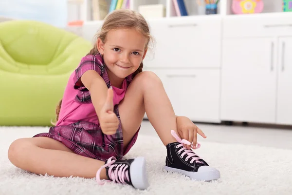 Маленька дівчинка вчиться зав'язувати взуття — стокове фото