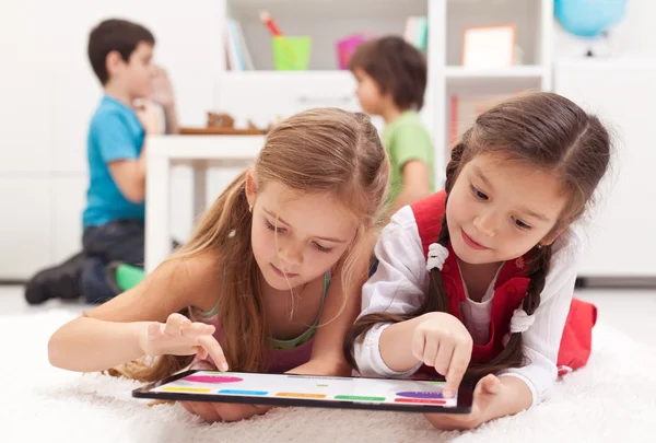 Små flickor spelar på en tablet datorenhet Royaltyfria Stockfoton