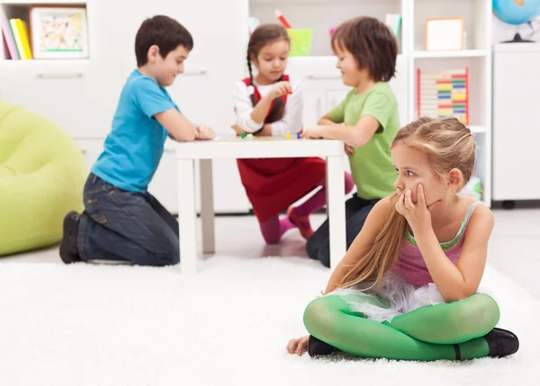 Kleines Mädchen, das auseinander sitzt - sich von den anderen ausgeschlossen fühlt — Stockfoto