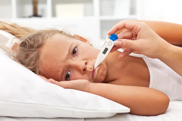 Krankes kleines Mädchen mit Thermometer liegt im Bett — Stockfoto