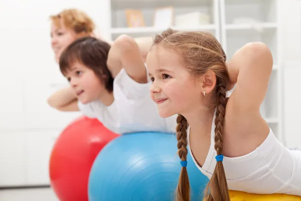 Niños y mujeres haciendo ejercicios con pelotas Imágenes De Stock Sin Royalties Gratis