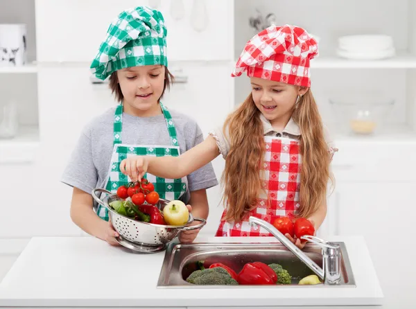 Crianças lavando legumes na cozinha — Fotografia de Stock