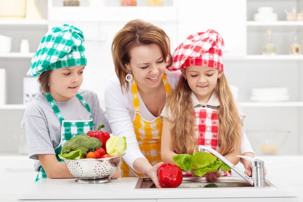 Mujer y niños preparando las verduras para una comida — Foto de Stock