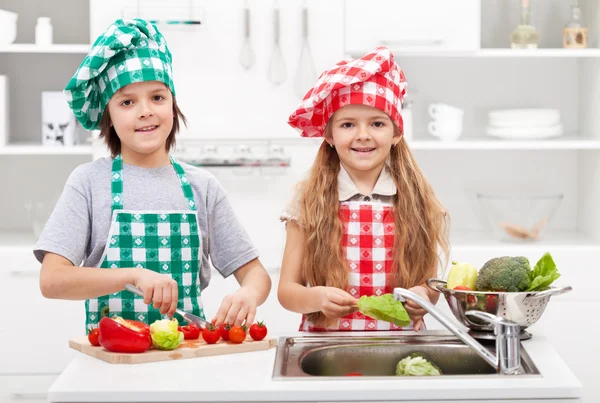 Niños ayudando en la cocina - lavando y cortando verduras — Foto de Stock