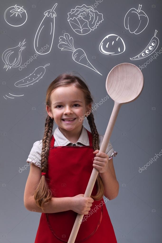Young girl with apron and large wooden spoon Stock Photo by ©ilona75