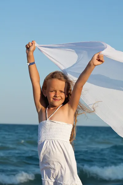 Liten flicka på havsstranden leker med en halsduk i vinden — Stockfoto