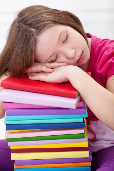 Erschöpftes junges Mädchen schläft auf Bücherstapel — Stockfoto