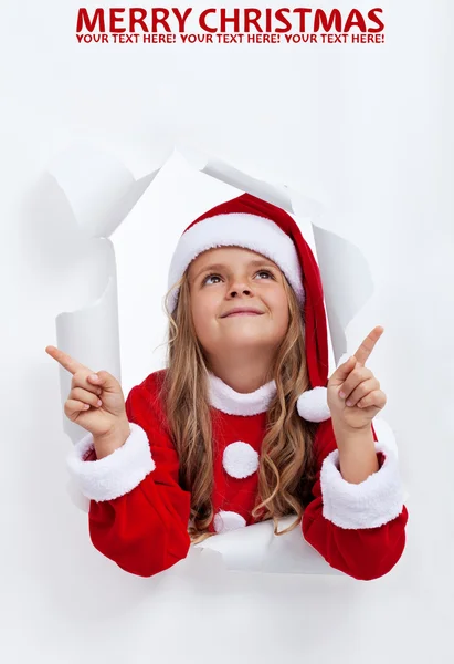 Happy santa girl at christmas pointing upwards to copy space — Stock Photo, Image