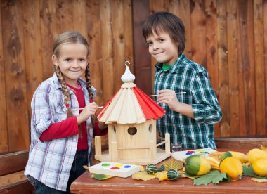 Kids painting the bird house - preparing for winter clipart