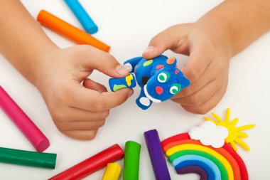 Child playing with colorful clay - closeup on hands clipart