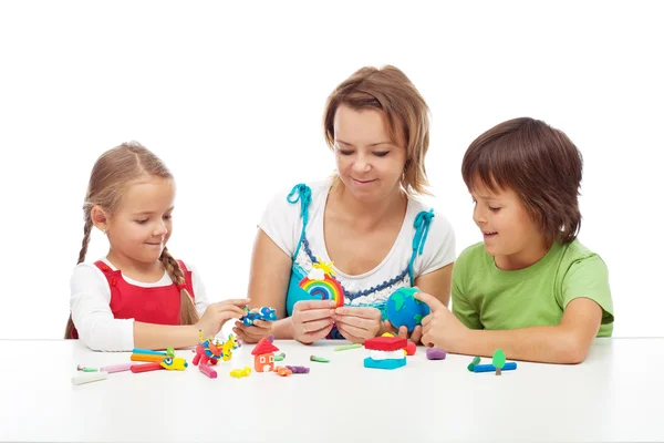 Mujer y niños jugando con arcilla colorida Imagen de archivo