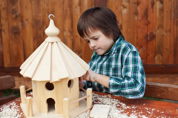 Pequeño niño haciendo los últimos toques finales en una casa de pájaros — Foto de Stock