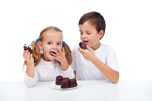 Šťastné děti jíst šlehačkou a čokoládou moučník — Stock fotografie