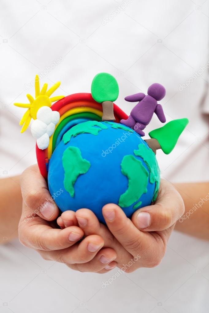 Modelling clay earth with rainbow and trees in child hands