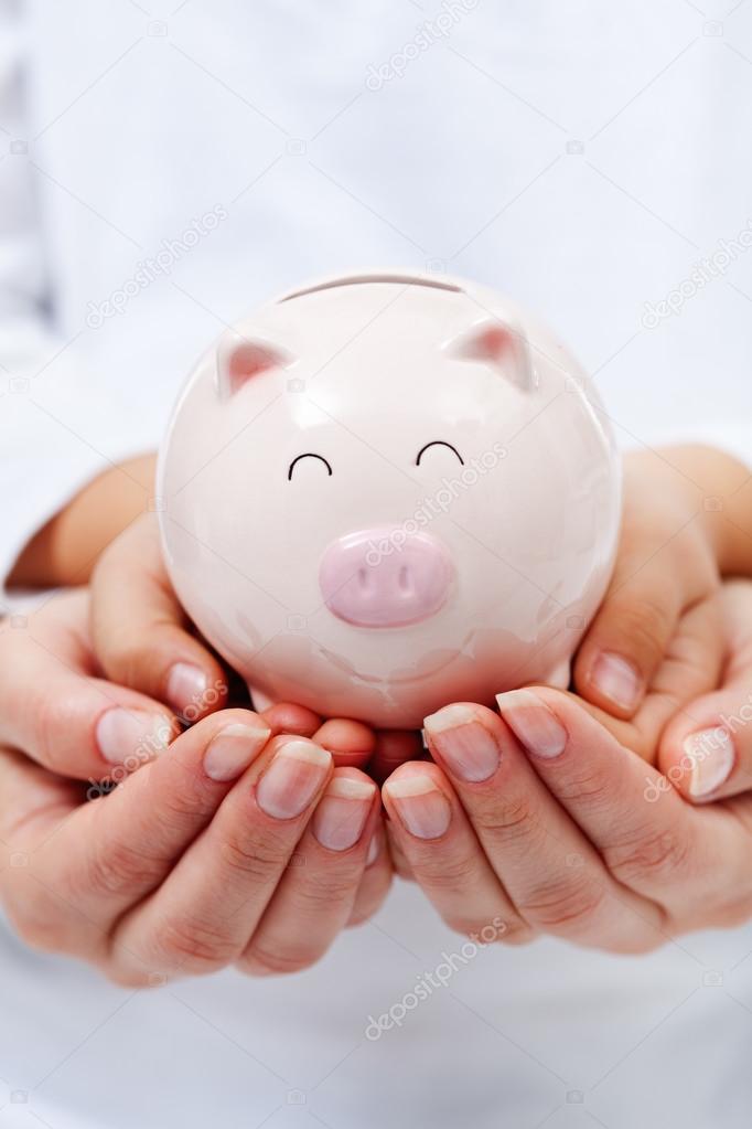 Cute small piggy bank in child hands