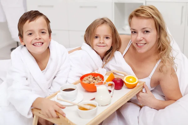 Frau frühstückt mit den Kindern im Bett — Stockfoto