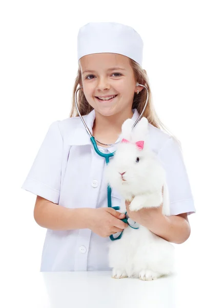 Маленькая девочка играет в ветеринара со своим кроликом — стоковое фото