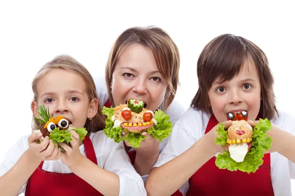 Woman and kids taking a bite from creative sandwiches — Stock Photo, Image