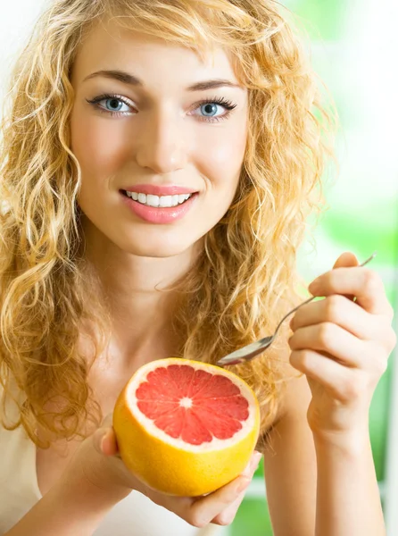 Fröhliche blonde Frau isst Grapefruit — Stockfoto