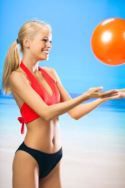 Ung kvinna leker med boll på stranden — Stockfoto