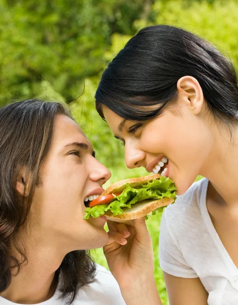 Young couple eating together outdoors — Stock Photo, Image