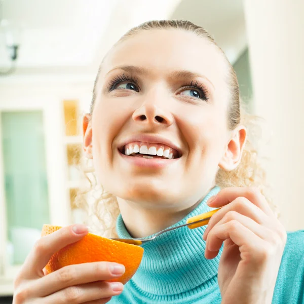 Vrolijke blonde vrouw eten grapefruit — Stockfoto