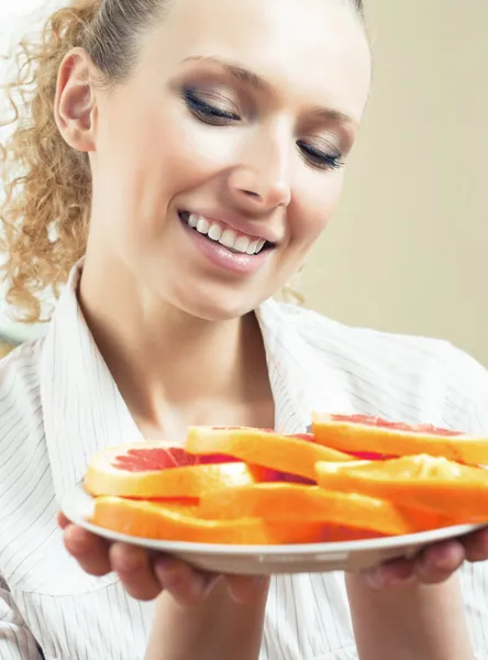 Mulher alegre com prato de laranjas e toranja — Fotografia de Stock